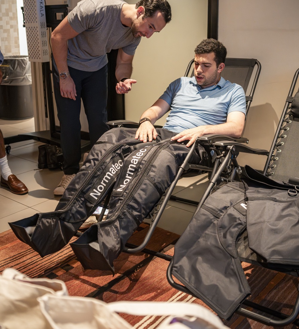 A guest recovering in Normatec compression boots at an NYC Health Collective event