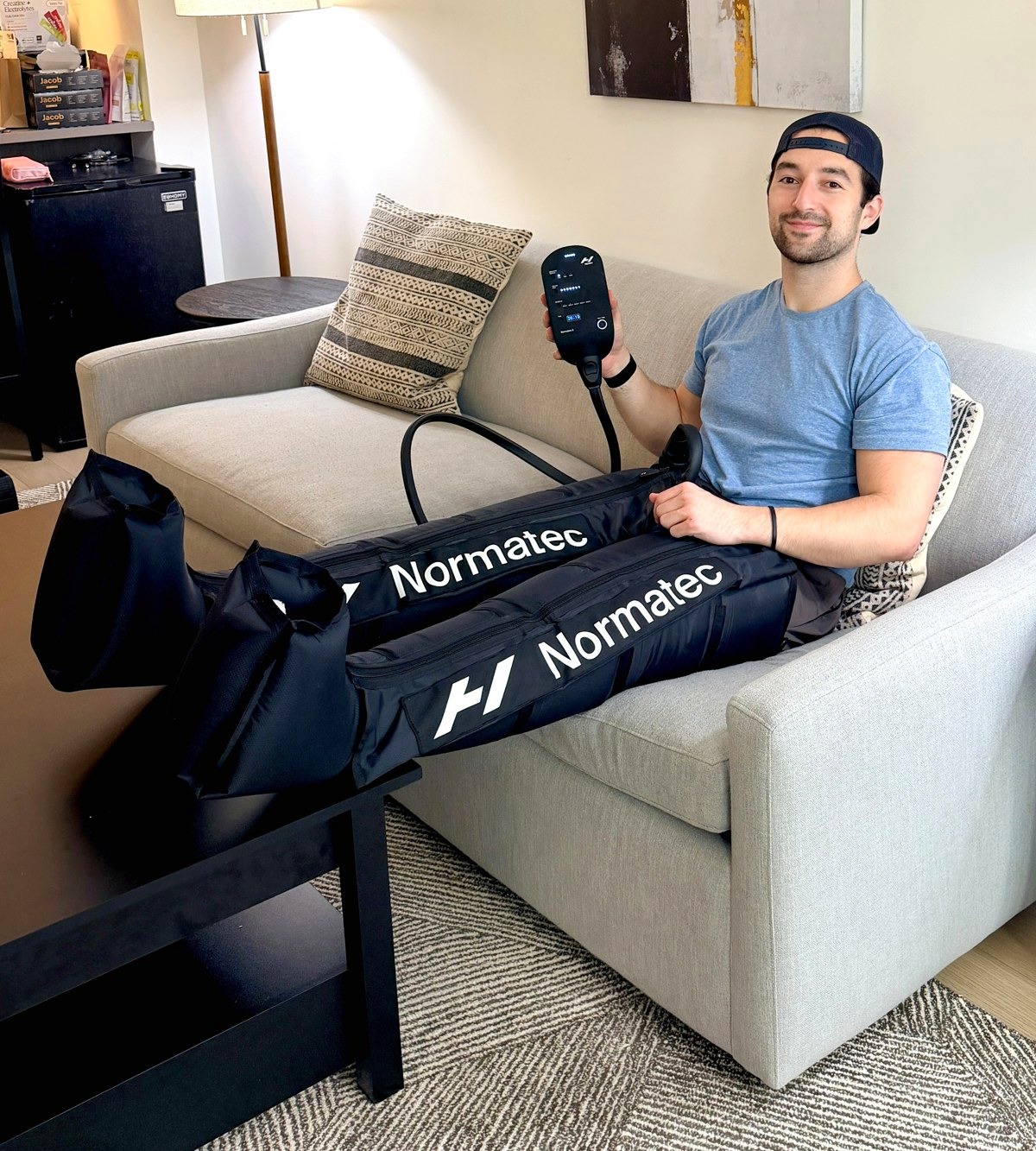 Adam relaxing on a couch using Normatec compression boots